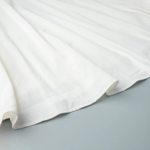 Gros plan détaillé de l'ourlet d'une robe blanche avec coutures et tissu de qualité