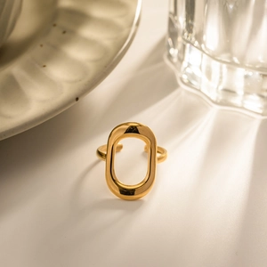 Macro shot of gold-plated hollow oval geometric ring on minimalist desktop setting
