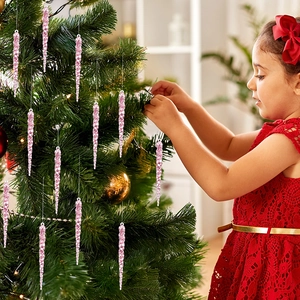 Pink acrylic icicle ornaments hanging on a Christmas tree with a festive girl nearby