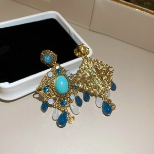 Detailed close-up of vintage gold earrings with blue turquoise stones and water drop beads