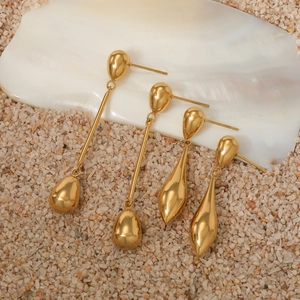 Elegant gold-plated long water drop earrings set displayed on natural sand and shells