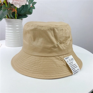 Detail of khaki canvas bucket hat with MERCI fabric label and metal eyelet accents