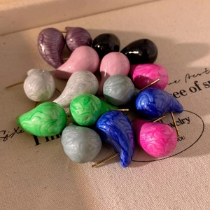 Waterdrop marble enamel earrings in various colors on textured canvas background