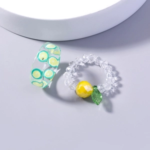 Macro shot of transparent resin rings featuring green lemon slices and a beaded fruit charm
