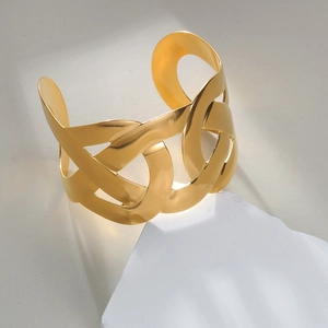 Macro detail of the 18K gold-plated wide cuff bracelet with a hollow interlocking chain design