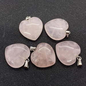 Macro detail of five heart-shaped pink quartz stone pendants with silver metal clasps