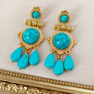 Detailed close-up of vintage gold earrings with turquoise stone teardrop pendants