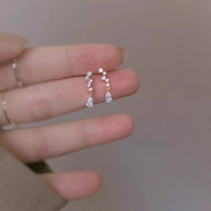 Exquisite teardrop zircon drop earrings in gold plating held by hand for display