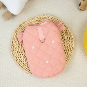 Detail of pink quilted dog vest with heart pattern, ruffles and metal D-ring for leash