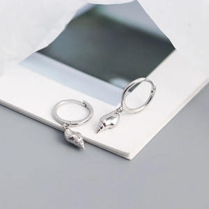 Detail of silver S925 shell drop earrings with polished conch pendants on hoop closures