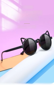 Detail view of stylish black cat-ear kids sunglasses with round dark grey lenses