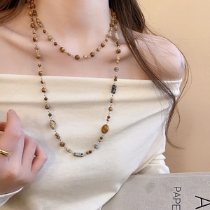 Close-up of double-layered beaded long necklace with gold-plated accents on a model