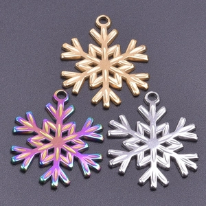 Detail of snowflake pendants in gold, silver, and rainbow finishes on textured background