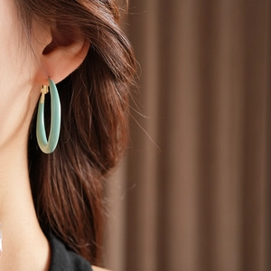 Gros plan d'un modèle portant des boucles d'oreilles créoles émaillées turquoise clair