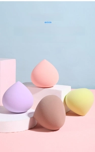 Detail of four water-drop makeup sponges in pink and lavender on geometric props