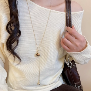 Detail of adjustable gold tiger eye heart necklace on white knit sweater