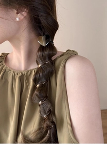 Close-up of heart-shaped brown hair tie and spiral resin coils used for braided hair
