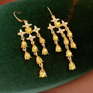 Detailed close-up of golden tassel earrings with yellow heart and teardrop gemstones