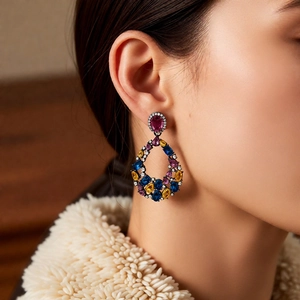 Macro shot of vintage teardrop earrings with colorful gemstones and black gold finish
