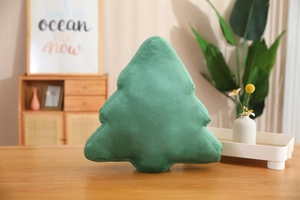 Detail view of a green plush Christmas tree pillow shell on a wooden table setup