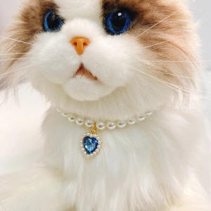 Elegant pet pearl necklace with a blue heart crystal pendant on a white cat model