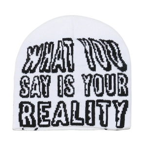 Detail of white knit beanie showing black jacquard text What You Say Is Your Reality