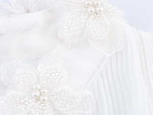 Detail von handgefertigten 3D-Blumen mit Perlen auf weißer plissierter Chiffon-Bluse