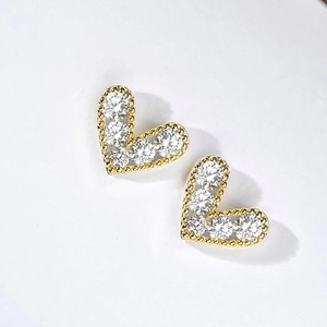 Macro detail of heart stud earrings with cubic zirconia inlay and millgrain gold edges