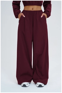 Detail of high-waisted burgundy wide-leg sports pants with elastic waist and side pockets
