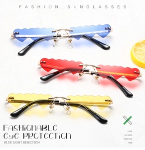 Vertical stack of heart-shaped rimless sunglasses in blue, red, and yellow on marble