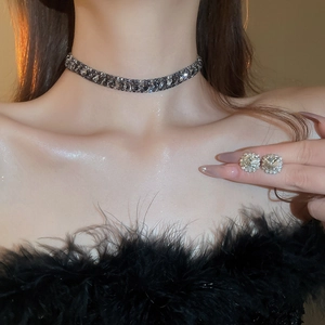 Close-up of vintage rhinestone flower necklace and square diamond studs on a model