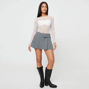 Detail view of sheer white mesh long sleeve top styled with a grey pleated mini skirt