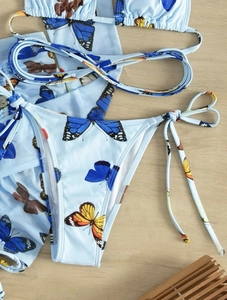 Detail view of butterfly print bikini set with matching mesh sarong on wooden background