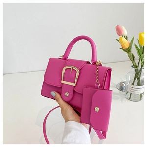 Detail of fuchsia leather crossbody bag featuring gold buckle and mini pouch accessory