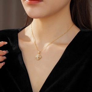 Détail d'un collier trèfle doré avec perle et cristaux porté par un mannequin