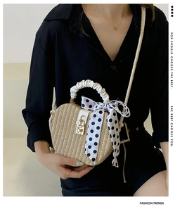 Detailed view of beige straw handbag featuring silk scarf and golden metal lock buckle