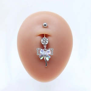 Close-up of silver belly ring with a sparkling bow pendant and iridescent detail