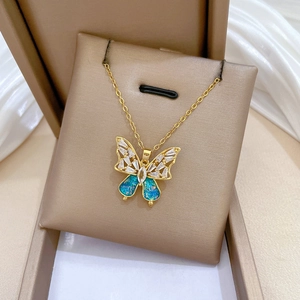 Detail of a gold butterfly necklace with blue inlay and crystals in a luxury box