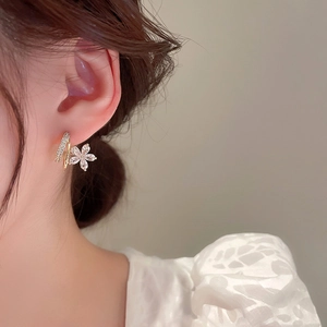 Détail d'une boucle d'oreille fleur en or avec pétales de zircon portée par un modèle