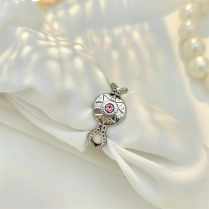 Detail of silver octagram star ring with pink gemstone on white silk and pearls