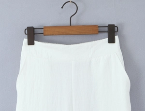 Dettaglio della texture del tessuto dei pantaloni casual bianchi su gruccia in legno