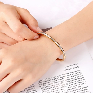 Close-up of gold stainless steel bracelet with white zircon inlay on fashion magazine
