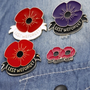 Detailed macro view of four enamel poppy pins with Lest We Forget text on denim fabric