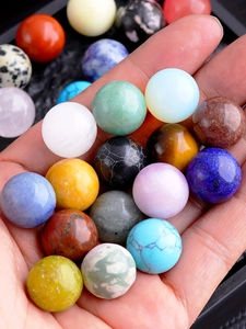 Close-up of hand holding various colorful polished 16mm natural crystal spheres