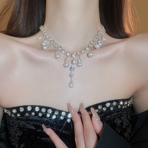 Close-up of elegant silver necklace featuring teardrop zircon and round pearl pendant