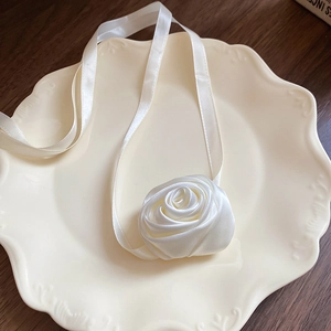 Collier ras du cou avec rose en satin blanc posé sur une assiette en céramique vintage