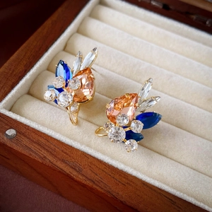 Macro shot of luxury teardrop crystal earrings in gold base on beige velvet box
