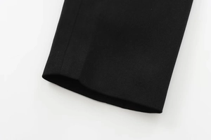 Detailed close-up of high-density black woven fabric with precise stitching on sleeve cuff