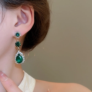 Detailed close-up of vintage style green teardrop earrings with crystal floral accents