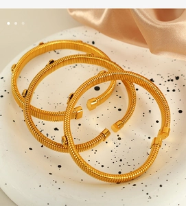 Detailed close-up of gold spiral textured bracelets with elegant clover charms